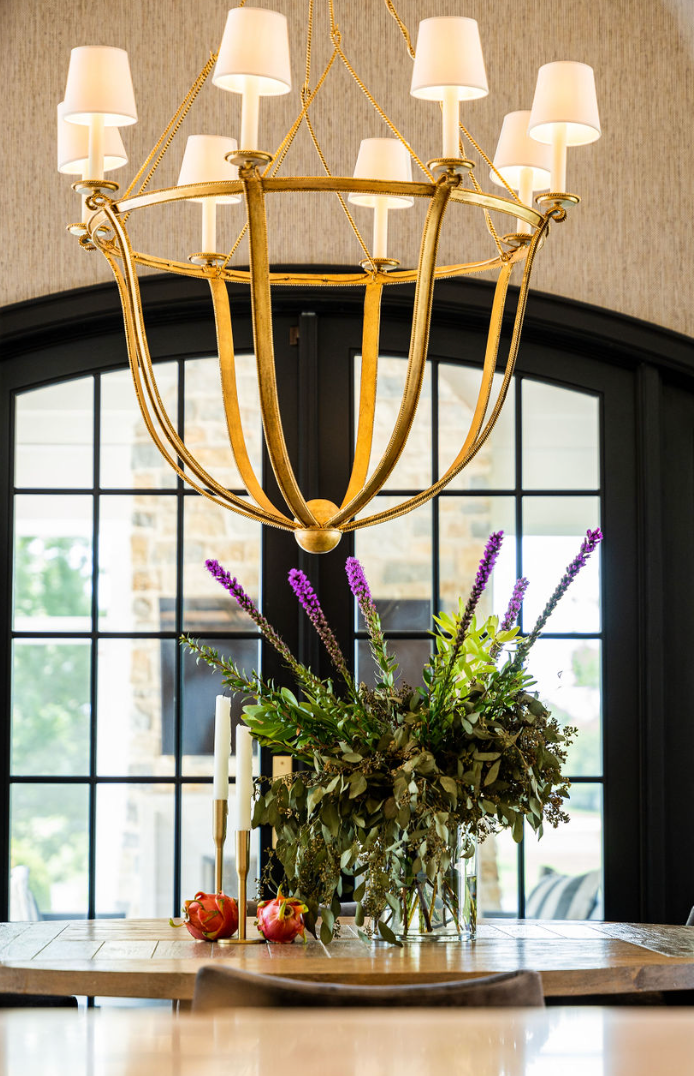 A chandelier is hanging over a table with flowers on it.