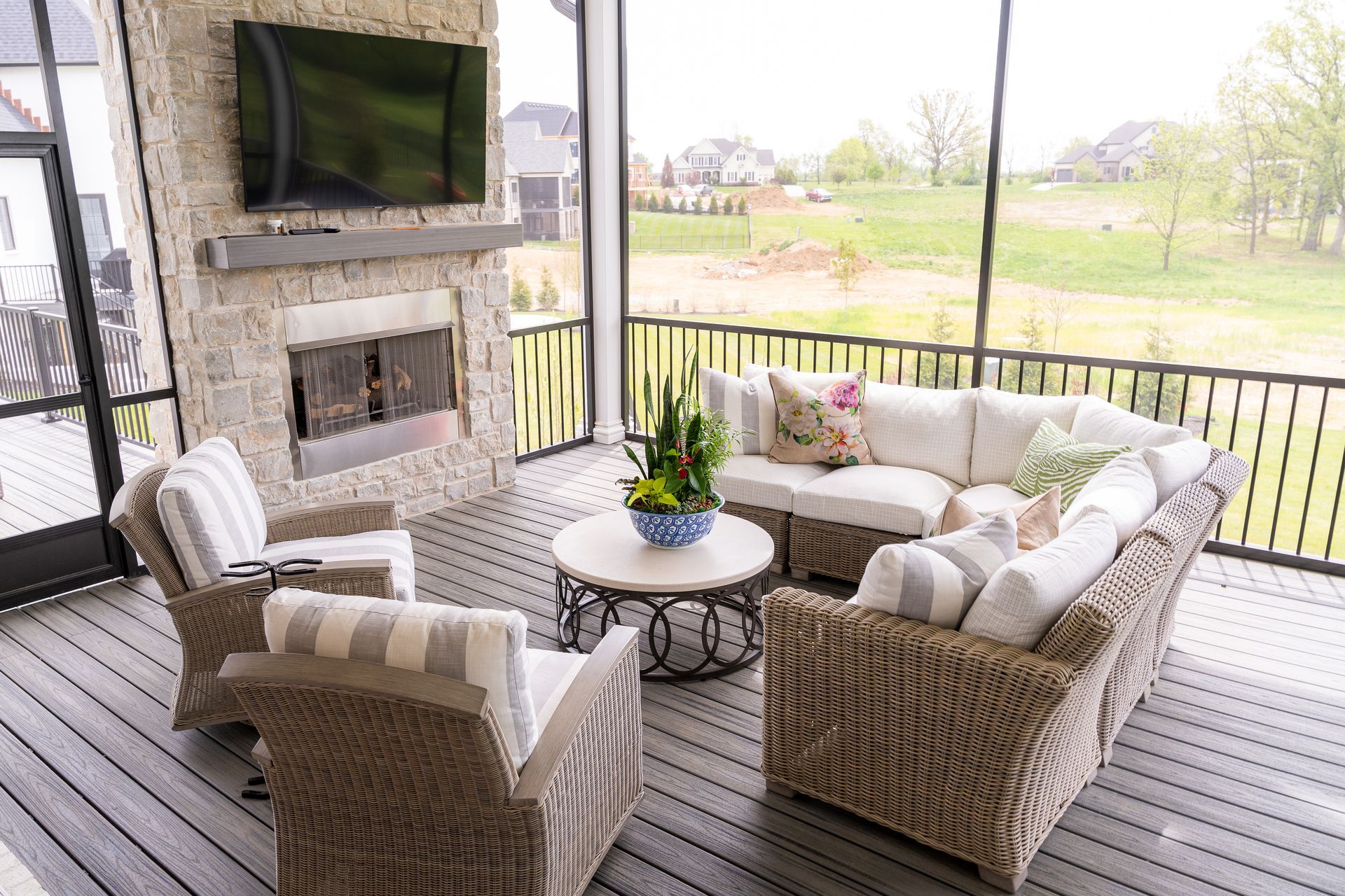 A screened in porch with wicker furniture and a flat screen tv.