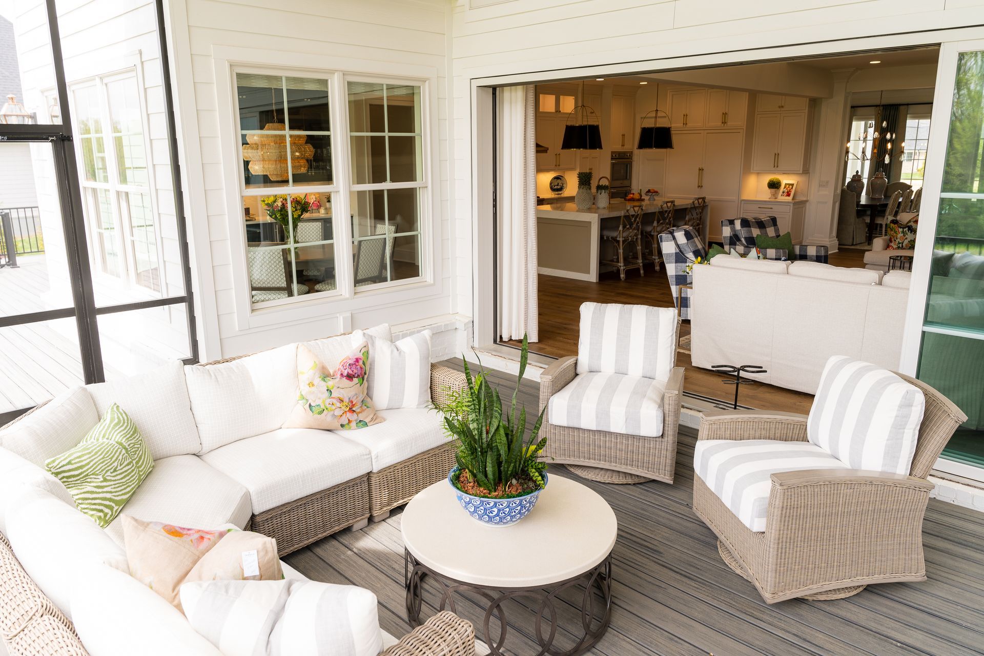 A patio with a couch , chairs , a table and a potted plant.