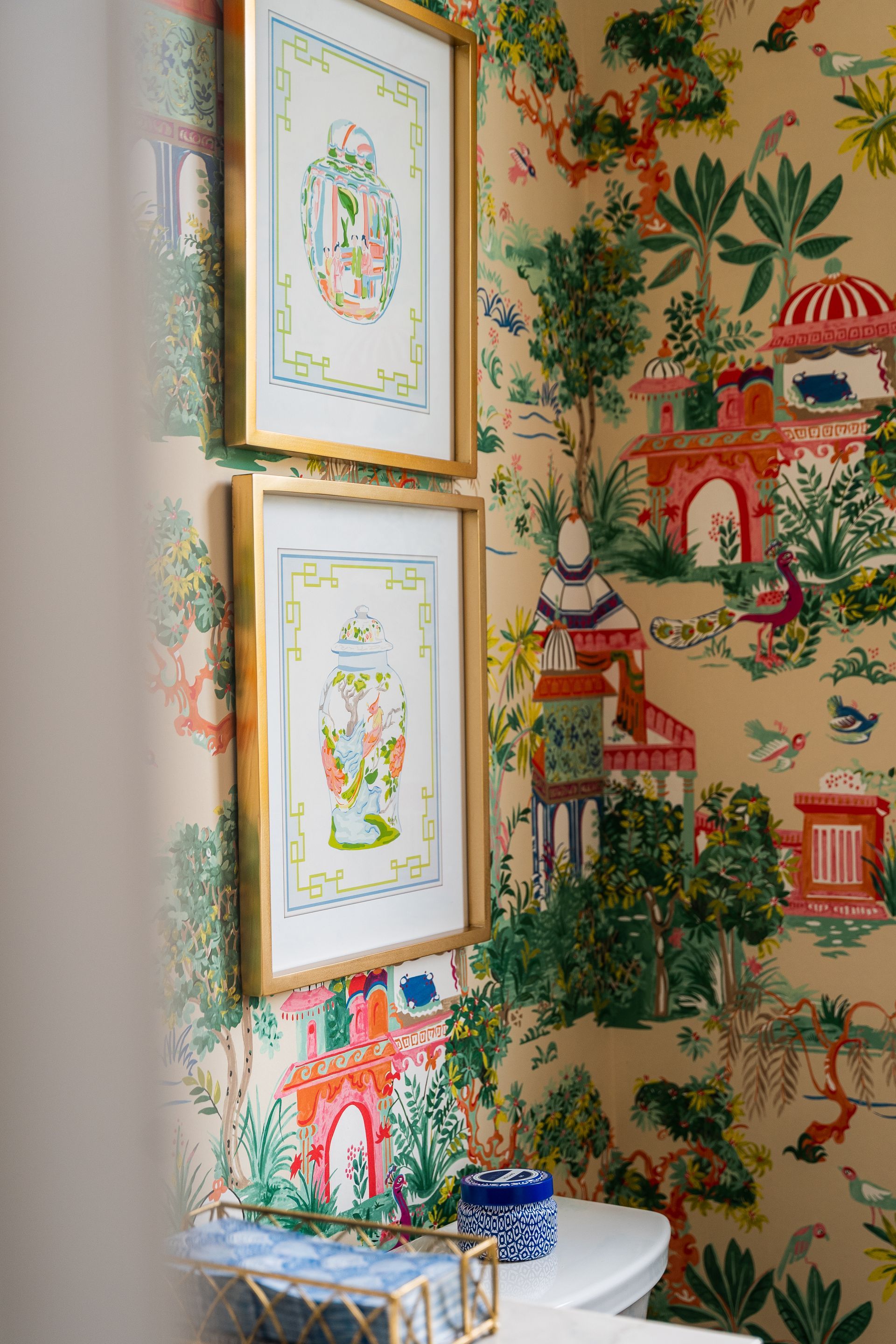 A bathroom with a toilet and two framed pictures on the wall.