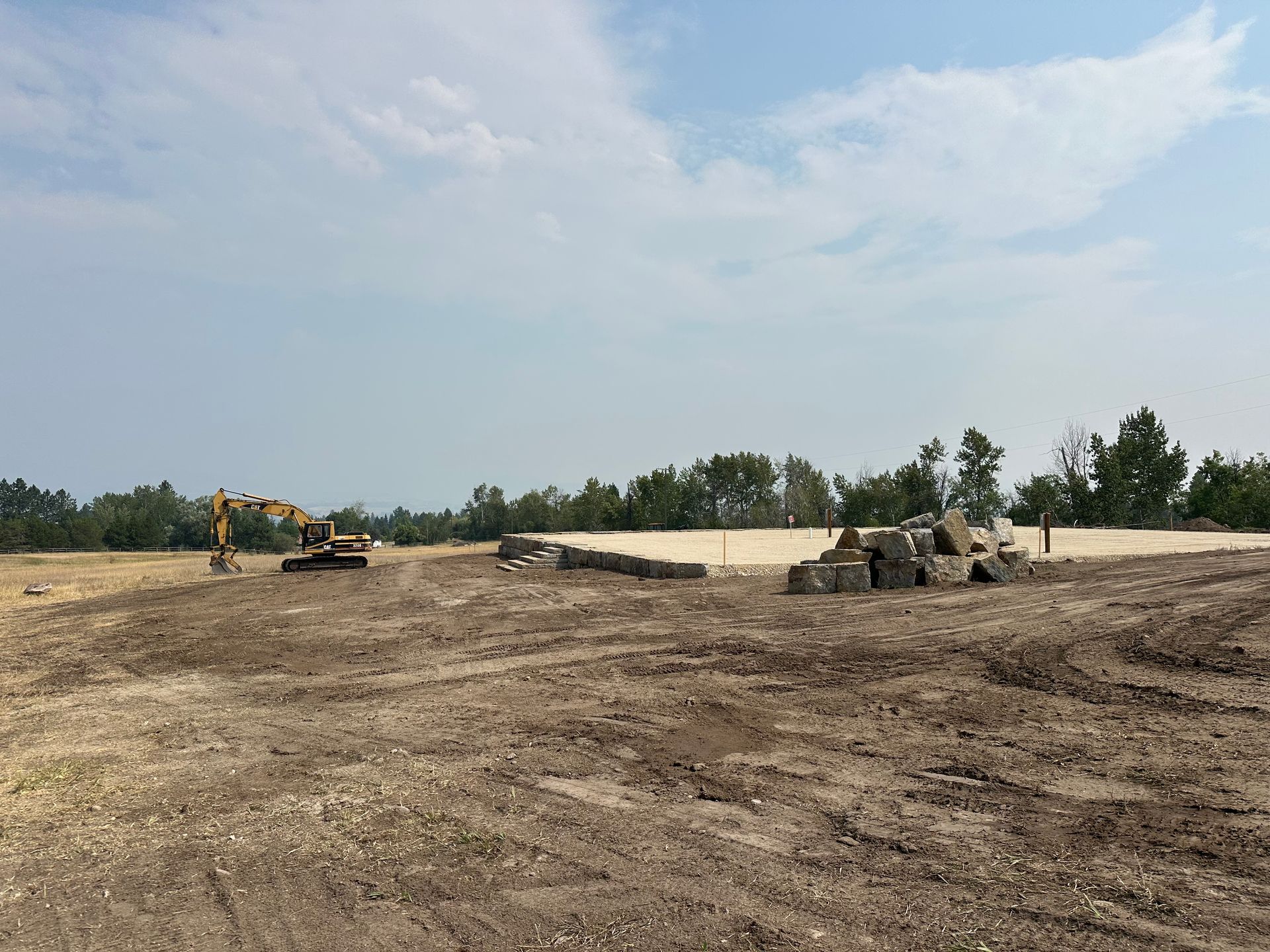 Construction site with heavy equipment and dirt piles under a cloudy sky