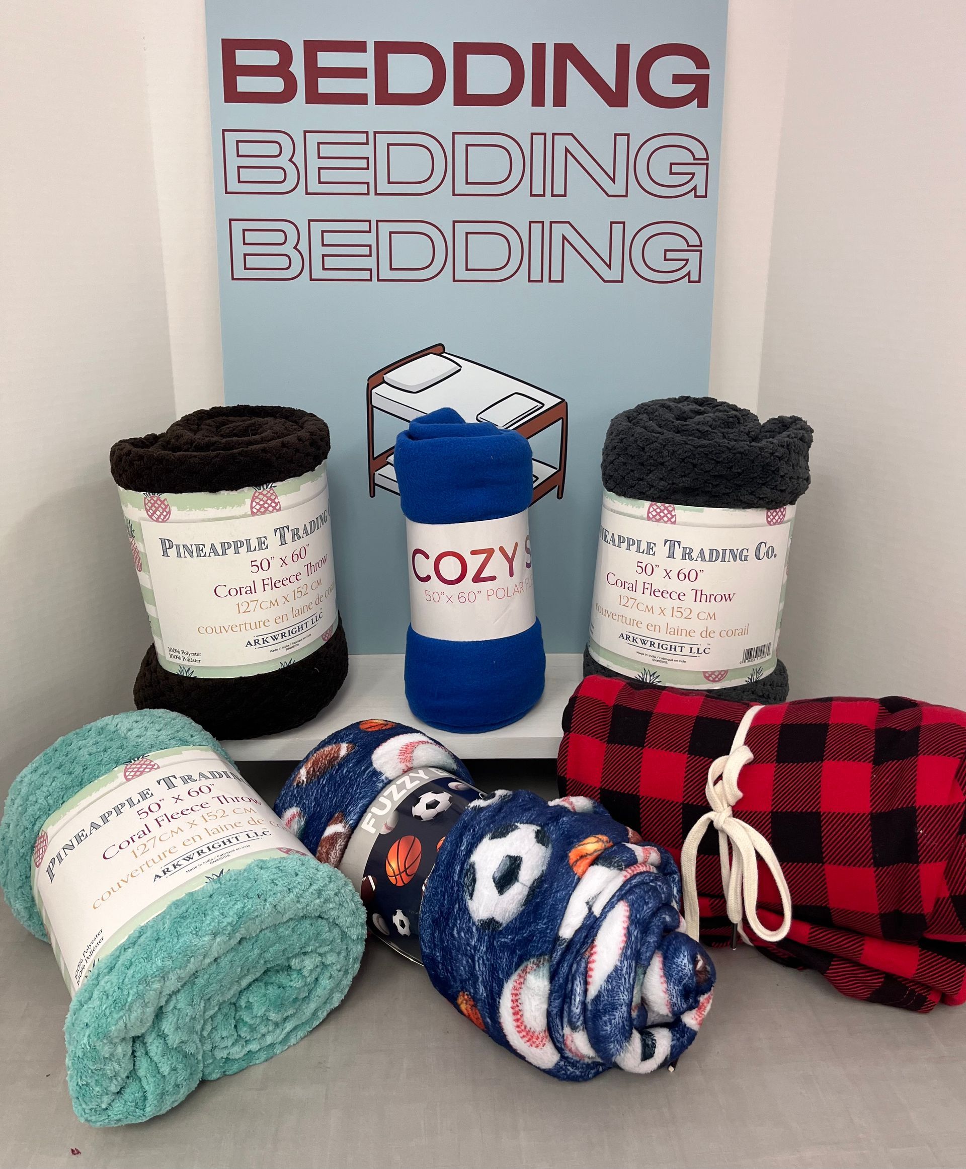 a bunch of blankets are stacked on top of each other in front of a sign that says bedding bedding bedding