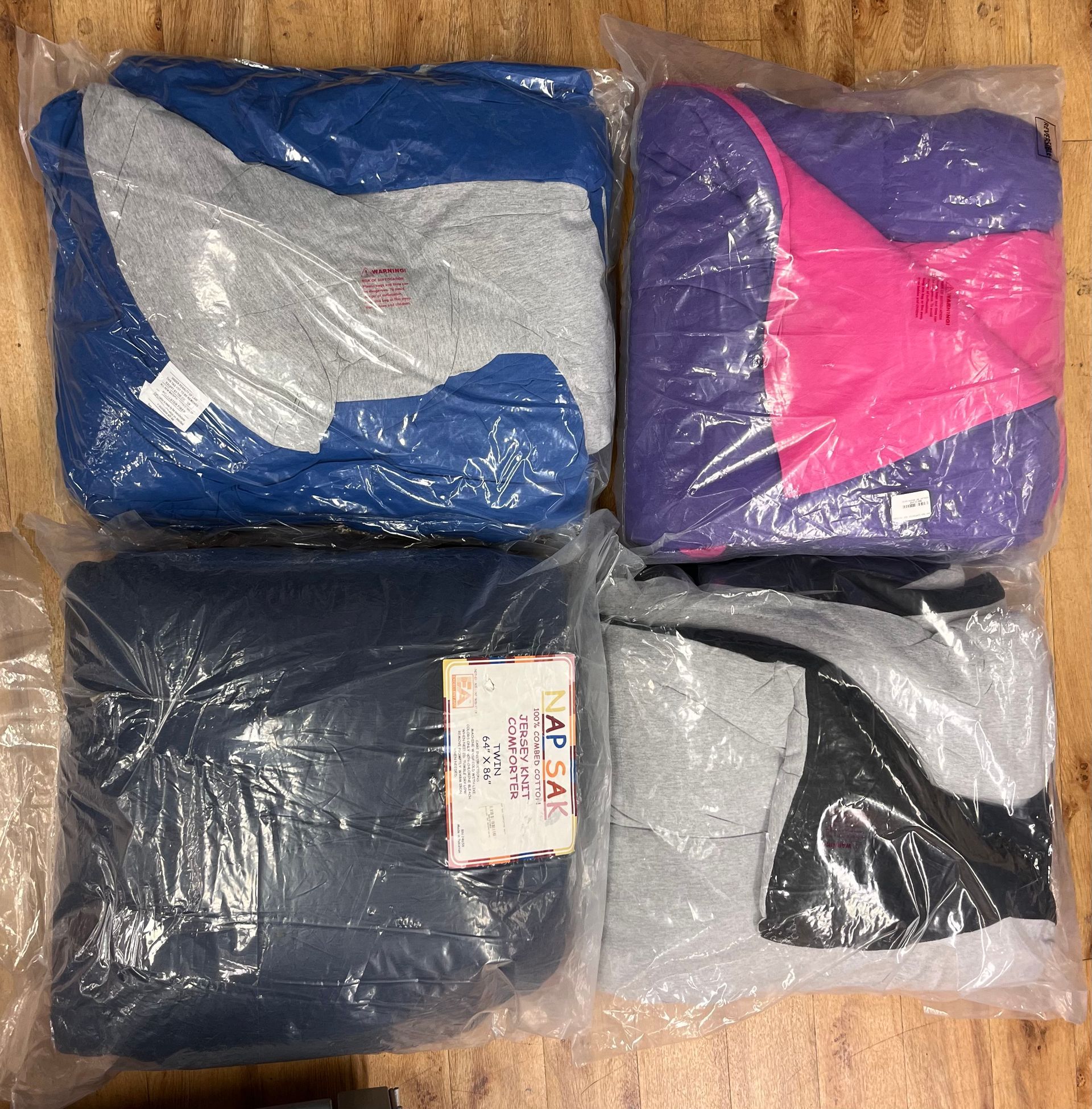 four bags of clothes are sitting on a wooden floor
