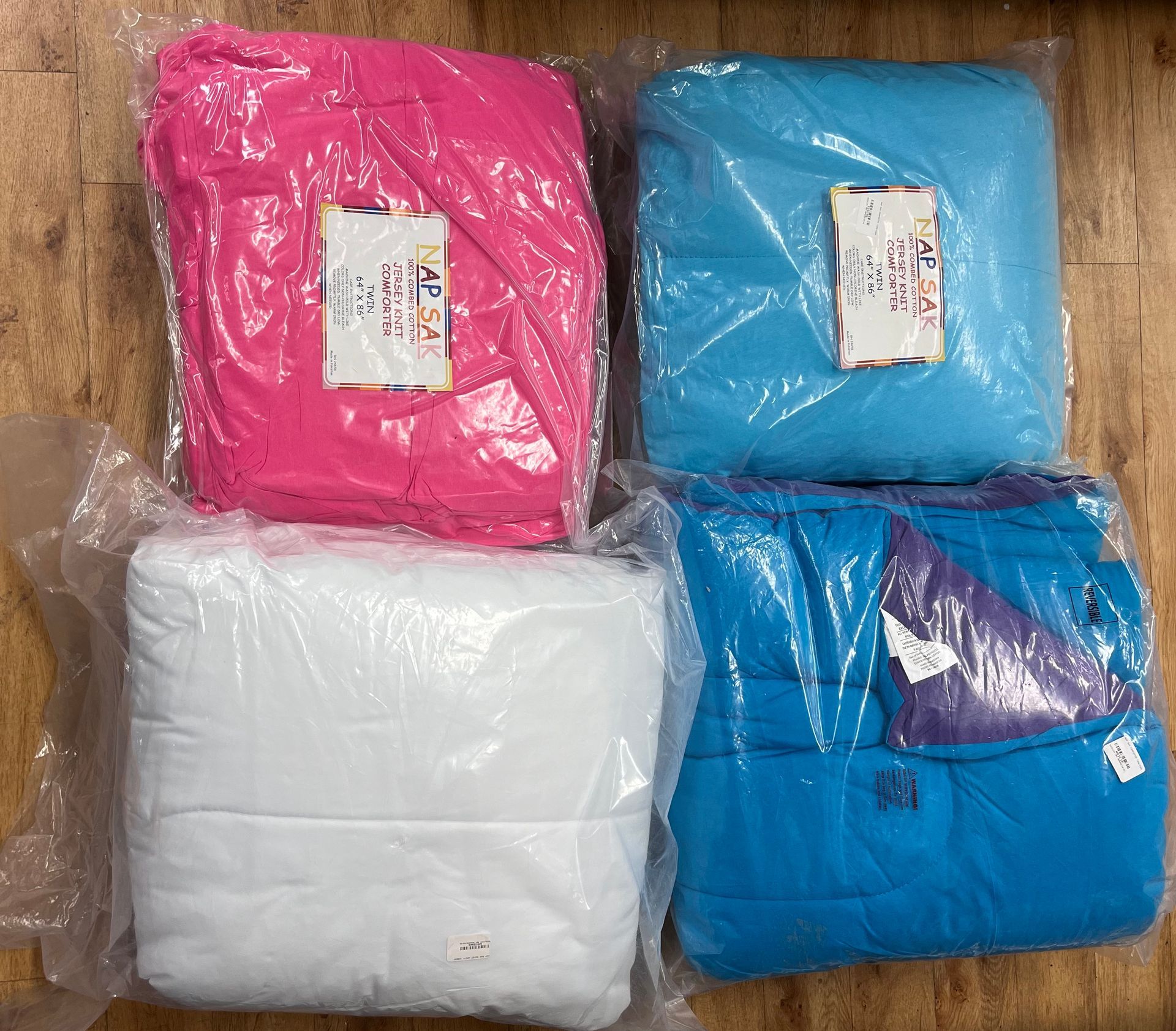 four different colored blankets are wrapped in plastic