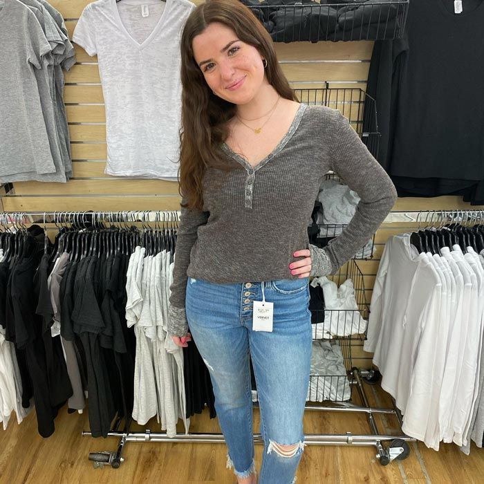 a woman is standing in front of a rack of clothes