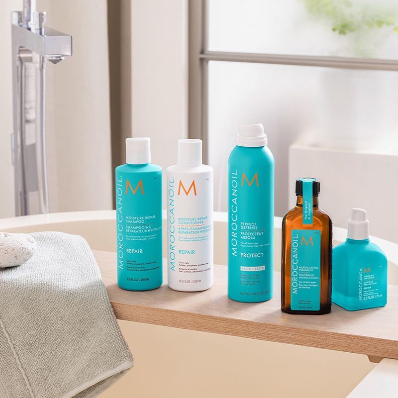 bottles of moroccanoil hair products are on a bathtub tray