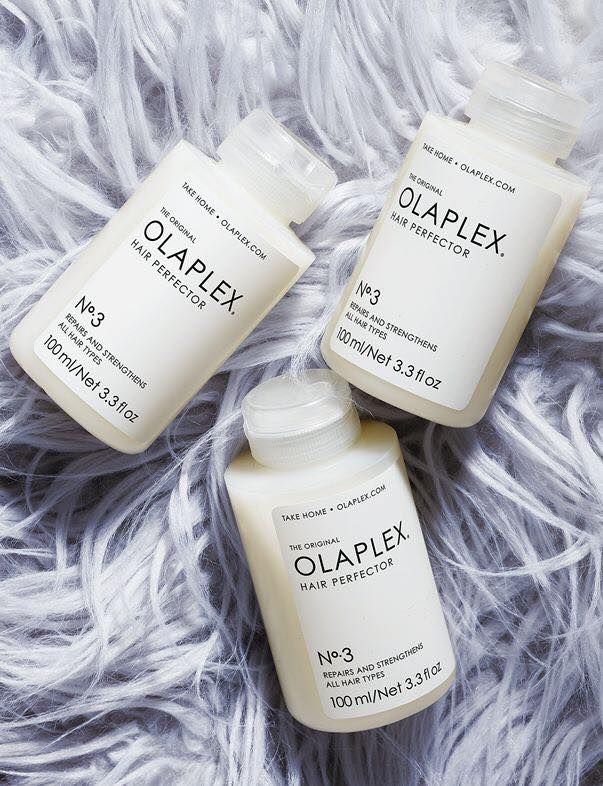 three bottles of olaplex hair products are sitting on top of each other on a furry surface .
