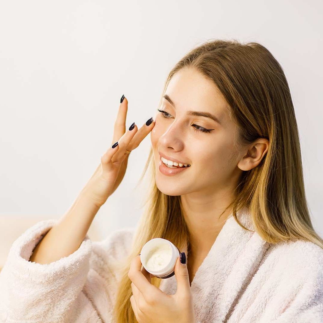 a woman is applying a cream to her face .