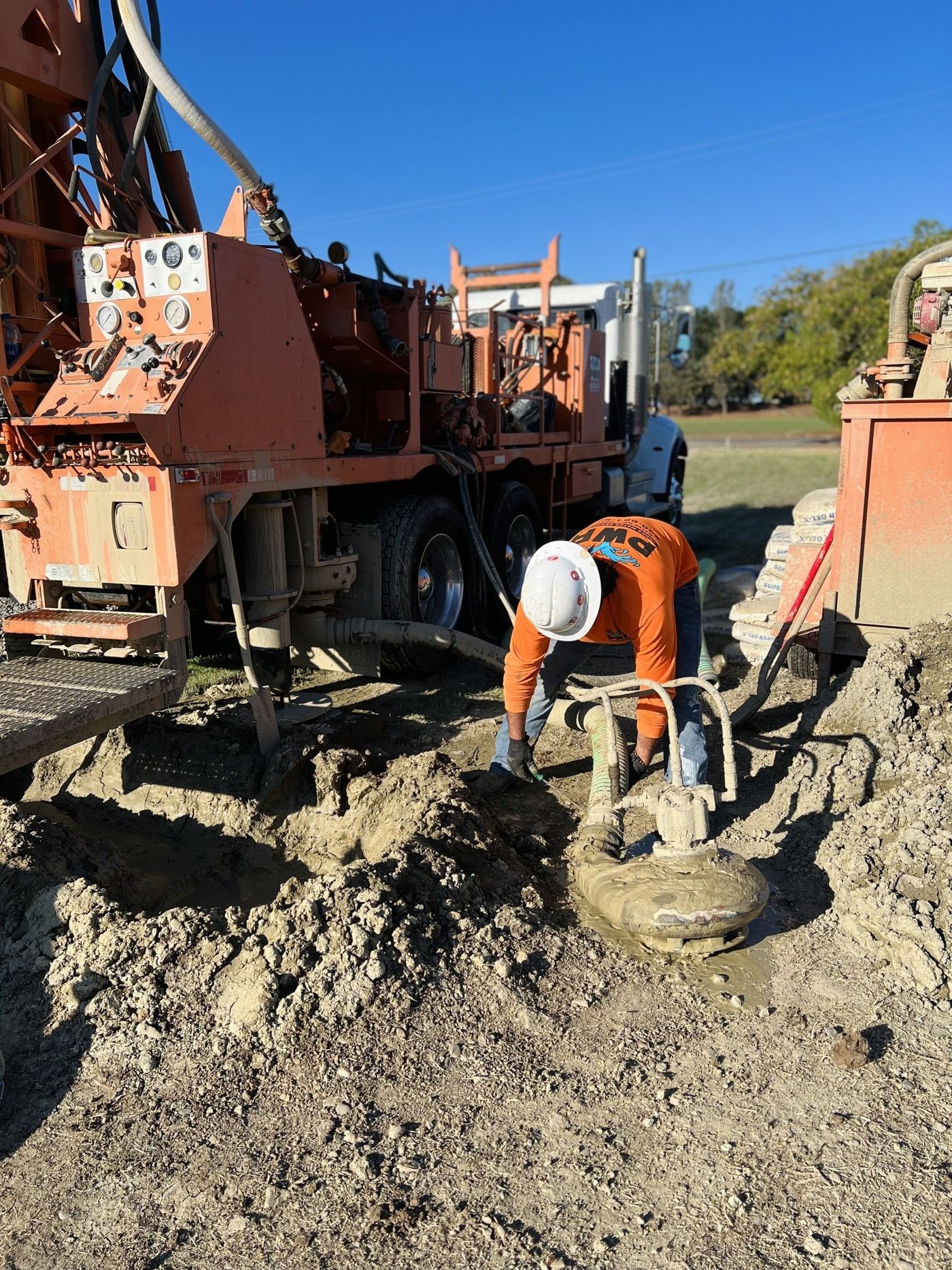 A man is digging a hole in the dirt in front of a truck.