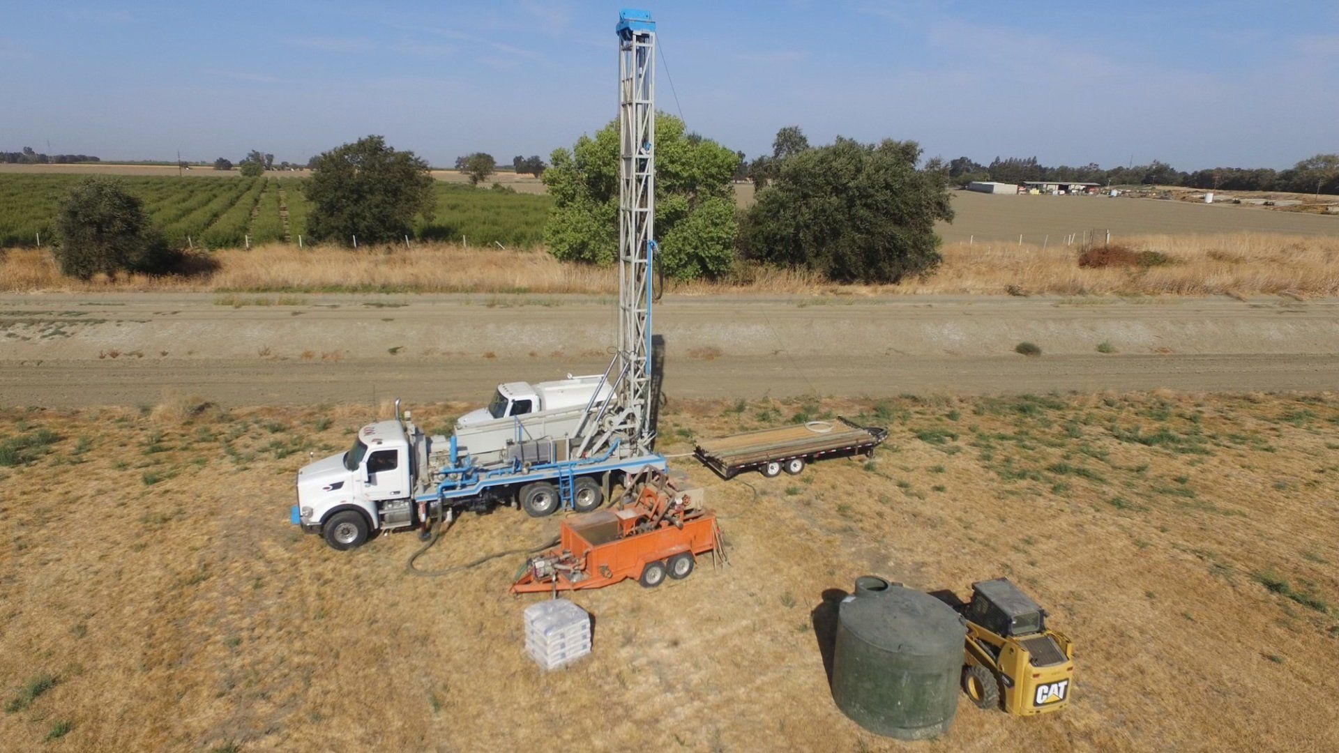 An aerial view of a truck and a drilling rig in a field.