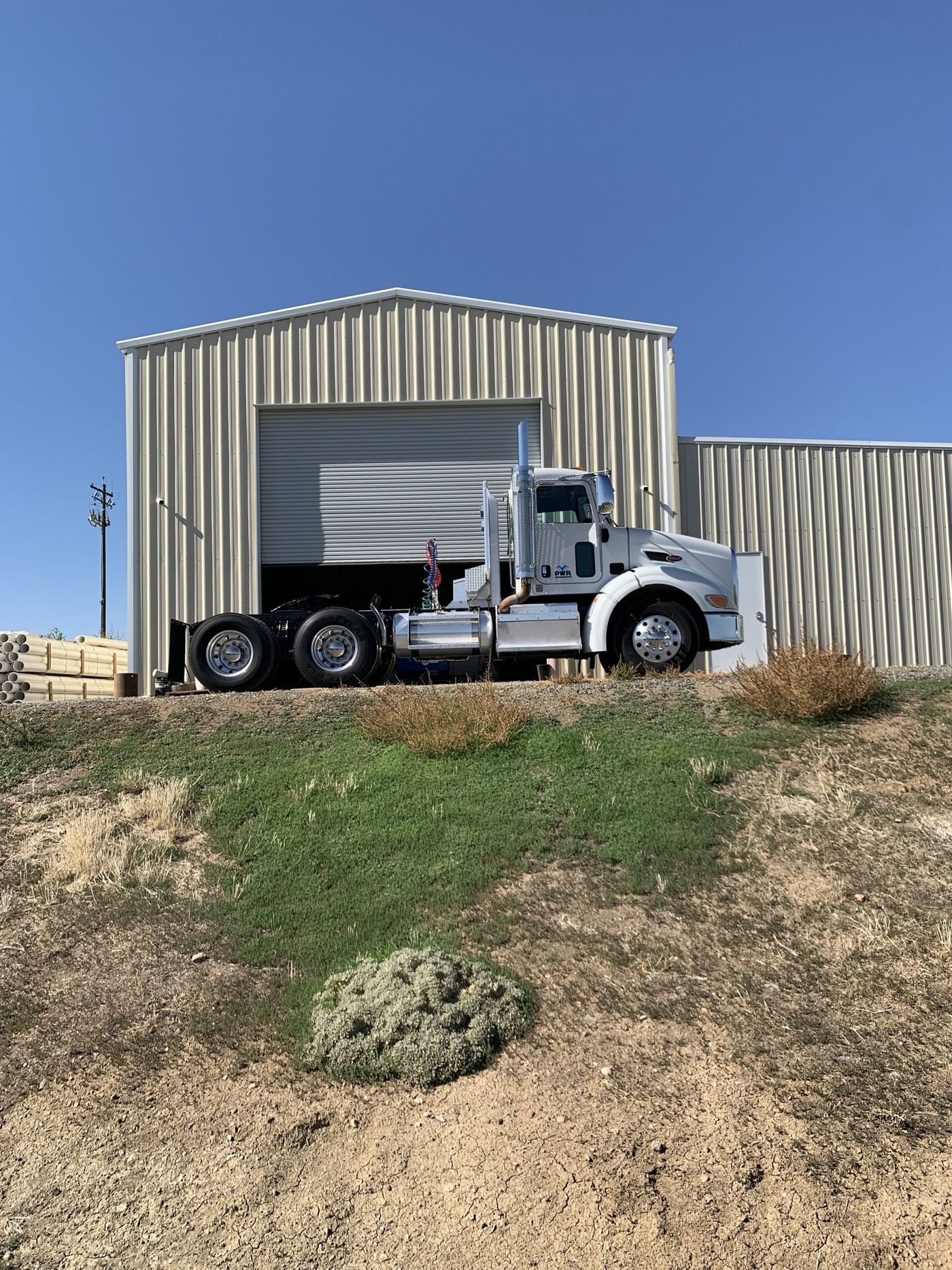 A semi truck is parked in front of a metal building.
