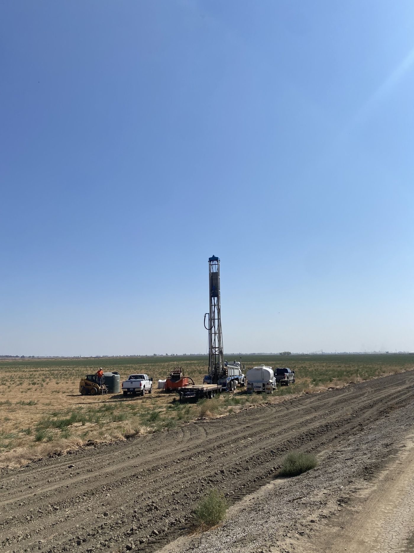 A large drilling rig is sitting in the middle of a dirt field.