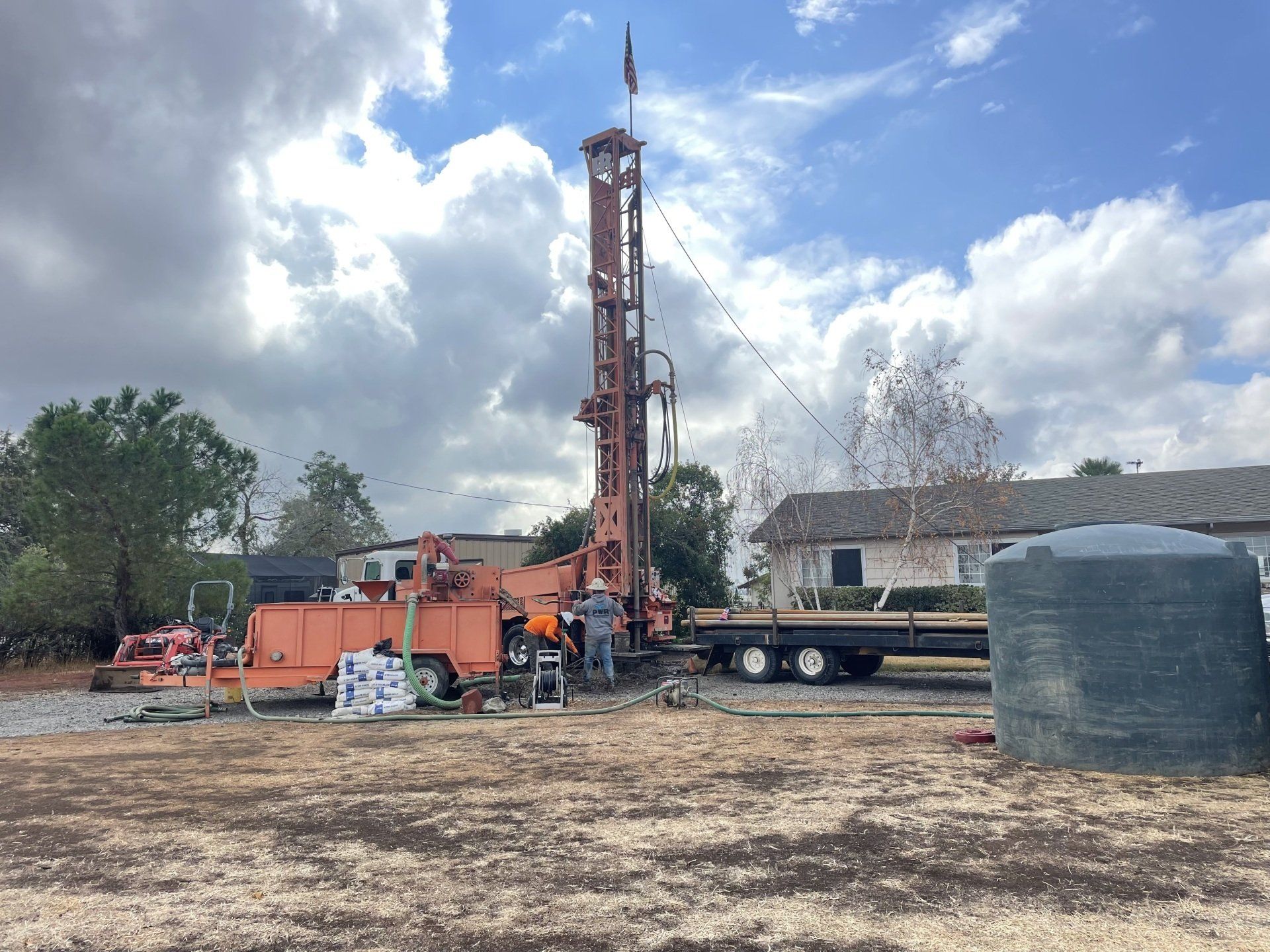 A large orange drilling rig is sitting in the middle of a field.