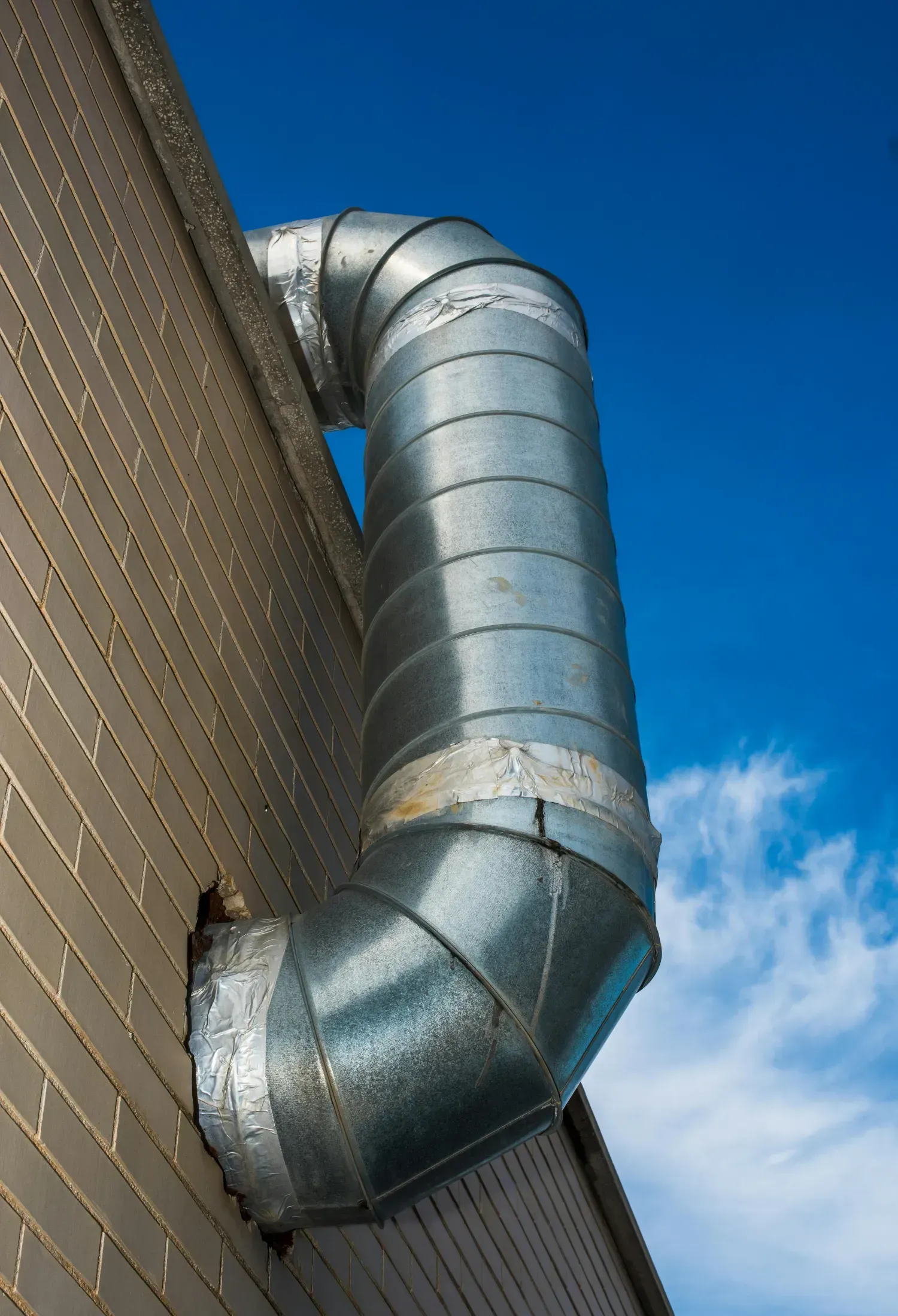 A metal pipe is attached to the side of a building.
