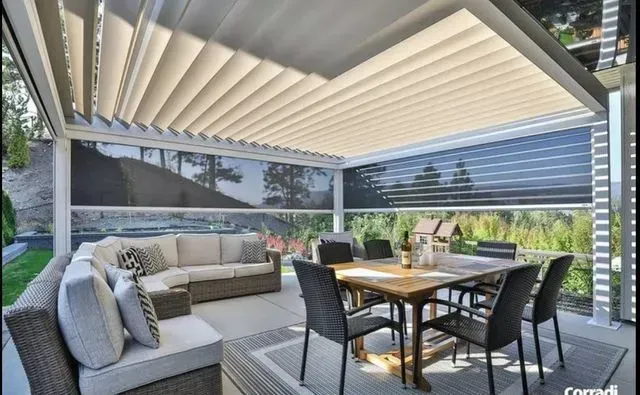 Covered patio with beige outdoor sectional, dining table, and black chairs overlooking a garden