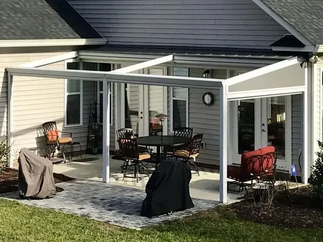 Patio with covered seating area, grill, and outdoor furniture beside a house