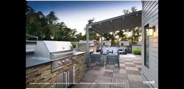 Modern outdoor patio with built-in grill, dining table, and pergola at dusk