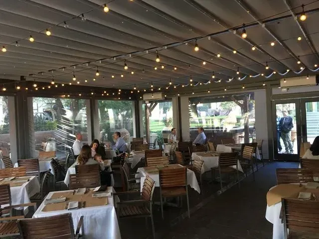 Open-air restaurant with diners seated at tables under string lights and a covered patio