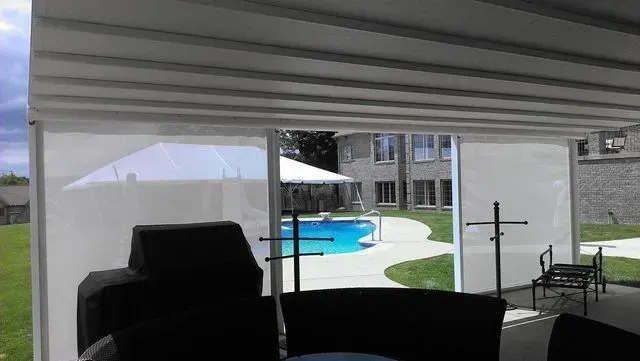 Covered patio overlooking a backyard pool and apartment building, with dark outdoor furniture in the foreground
