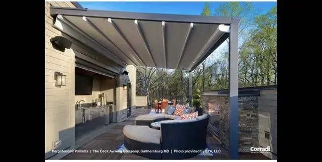 Covered patio with retractable awning, outdoor sofa, and fire pit in a backyard garden.