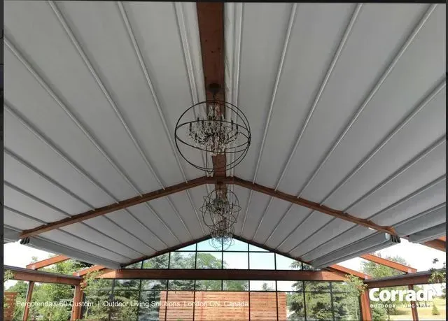 Covered patio ceiling with white panels, exposed wood beams, and a hanging light fixture.