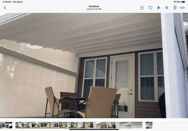 Covered patio with table and chairs beside a house entrance and windows