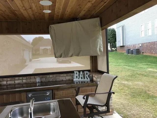 Covered patio with bar counter, chair, and hanging cloth screen overlooking a yard