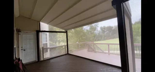 Empty covered porch with wood floor, white ceiling, and railing overlooking a green yard