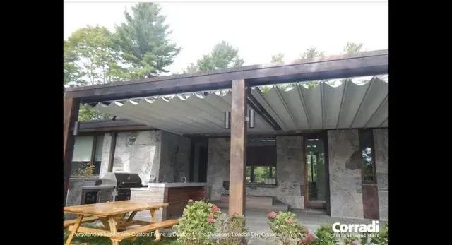 Modern patio with dark pergola, picnic table, and outdoor seating beside a stone house
