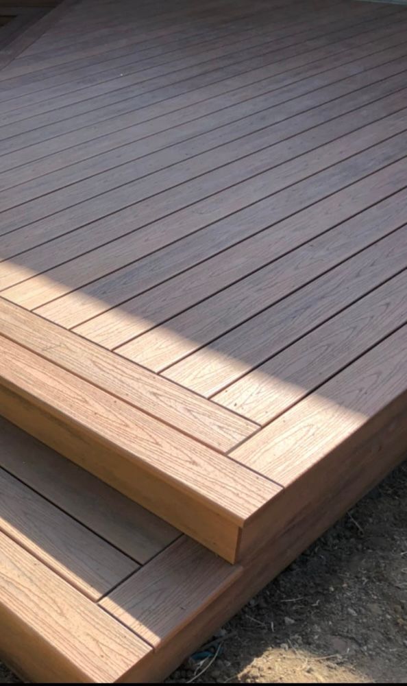 Deck construction, builder hand with electric screwdriver installing impregnated wooden boards