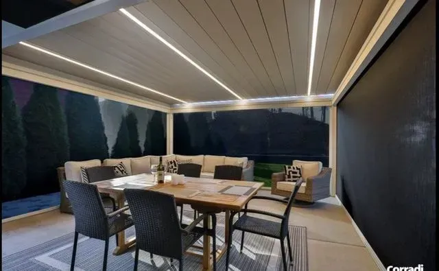 Covered outdoor patio with dining table, chairs, and warm LED lighting at dusk