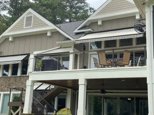 Two-story house with beige siding, white trim, and a covered deck with outdoor furniture