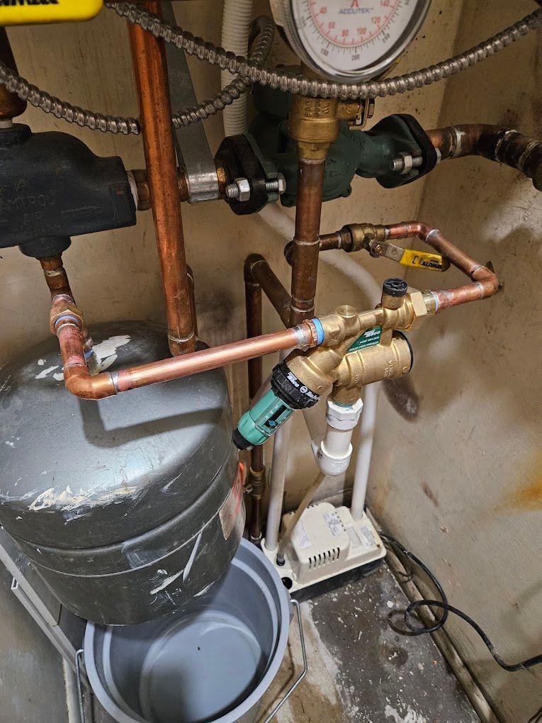 A close up of a water pump with copper pipes and a pressure gauge.