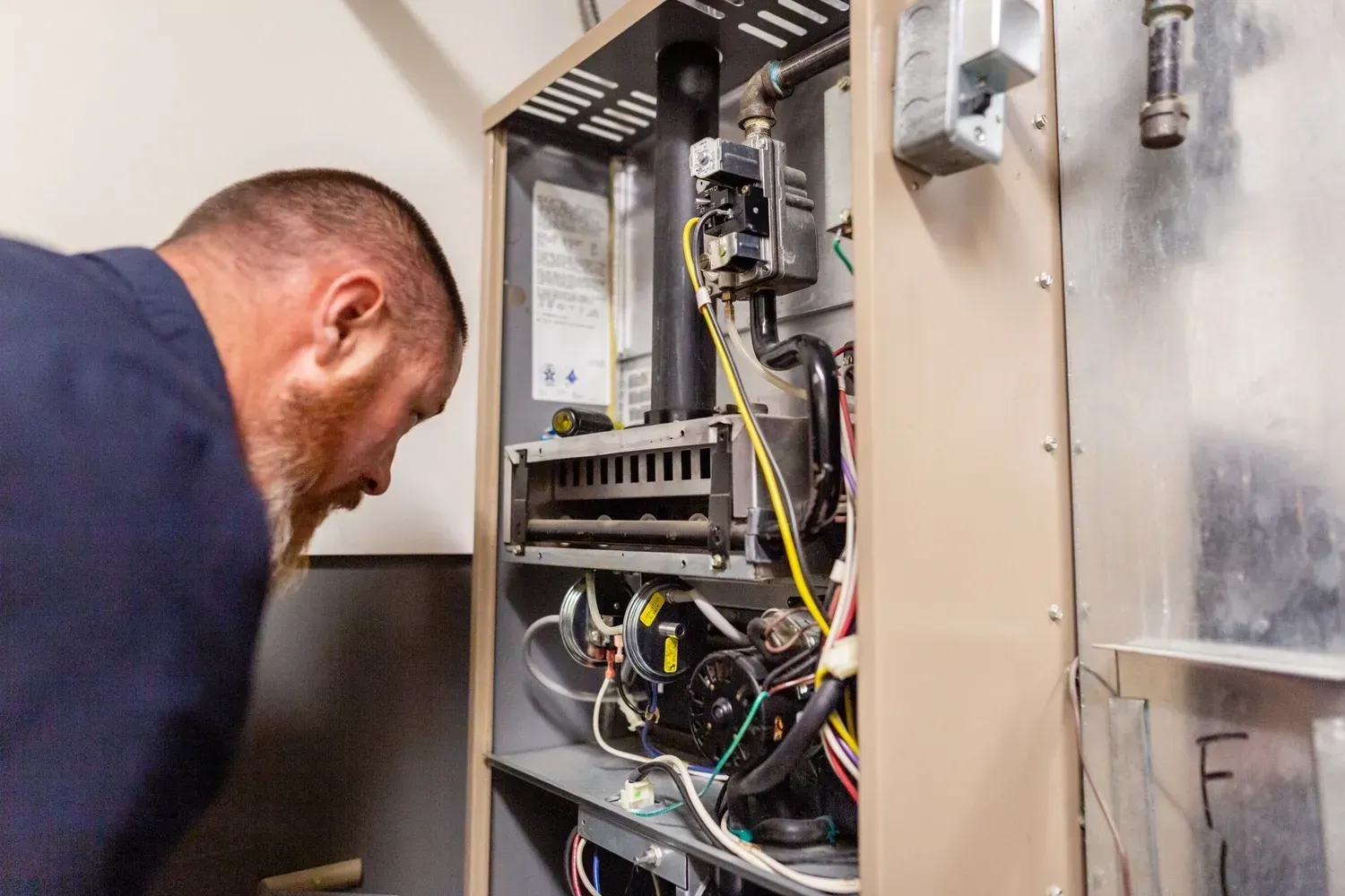 A man is working on a heating system in a house.