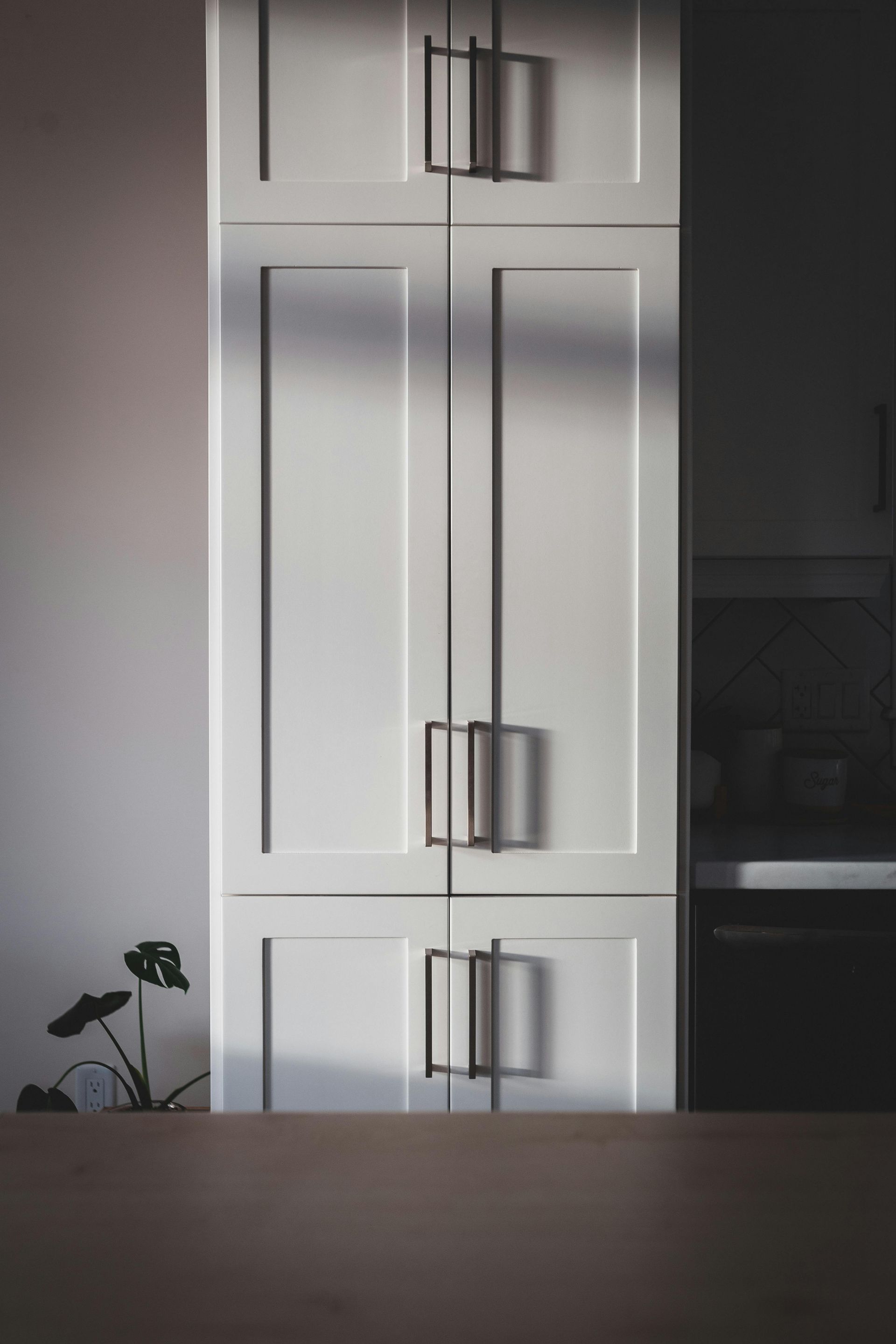 A kitchen with white cabinets and black handles.