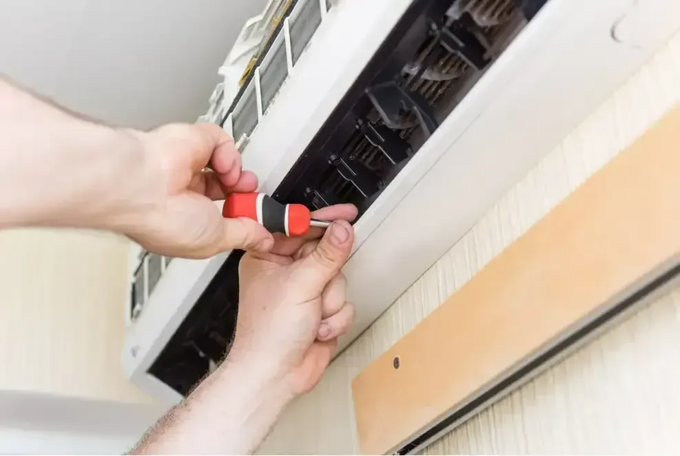 A Person is Fixing an Air Conditioner With a Screwdriver — Airac Sales & Service in Berserker, QLD