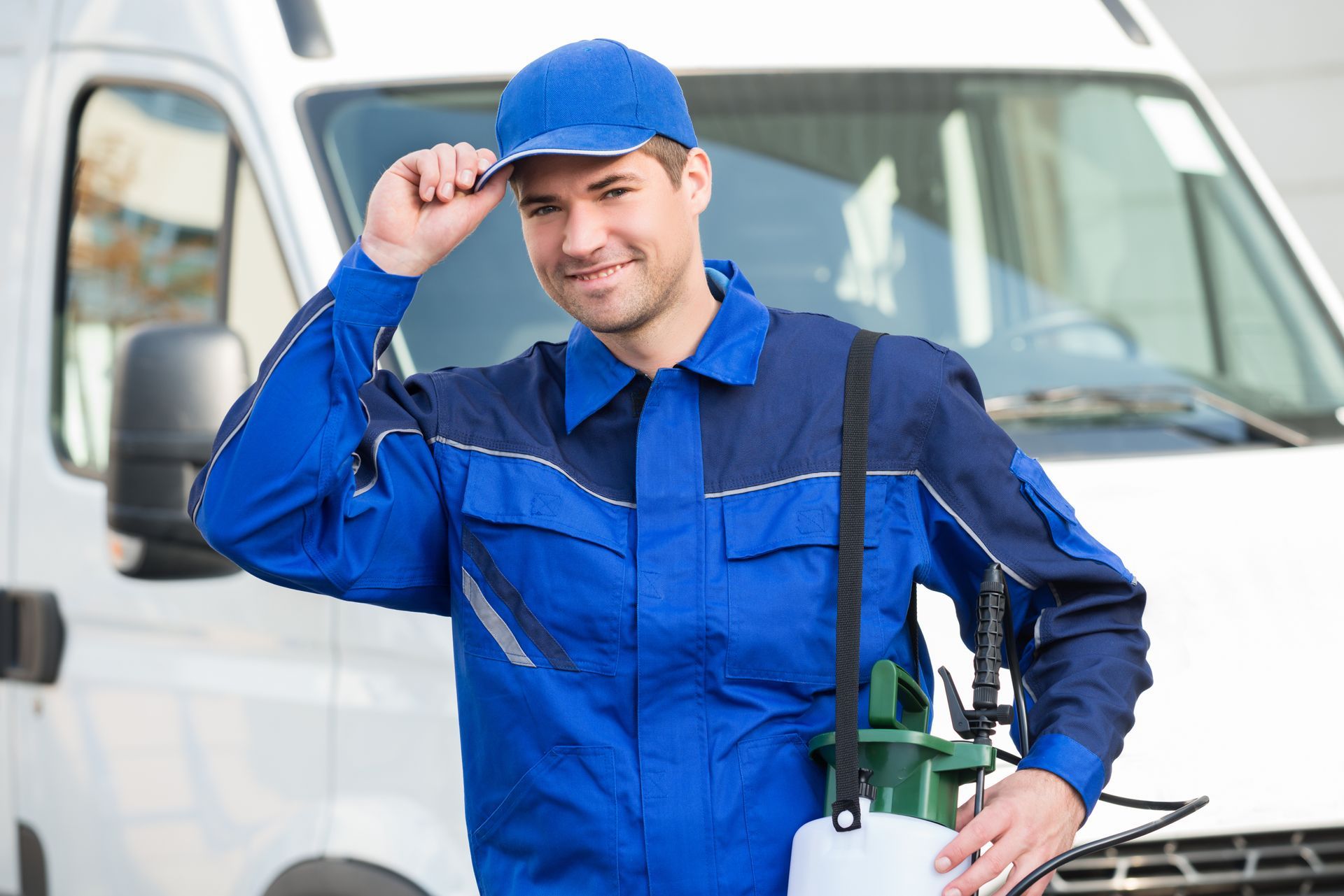 Pest control technician with sprayer standing in front of a service van. Pest control technician with sprayer standing in front of a service van.