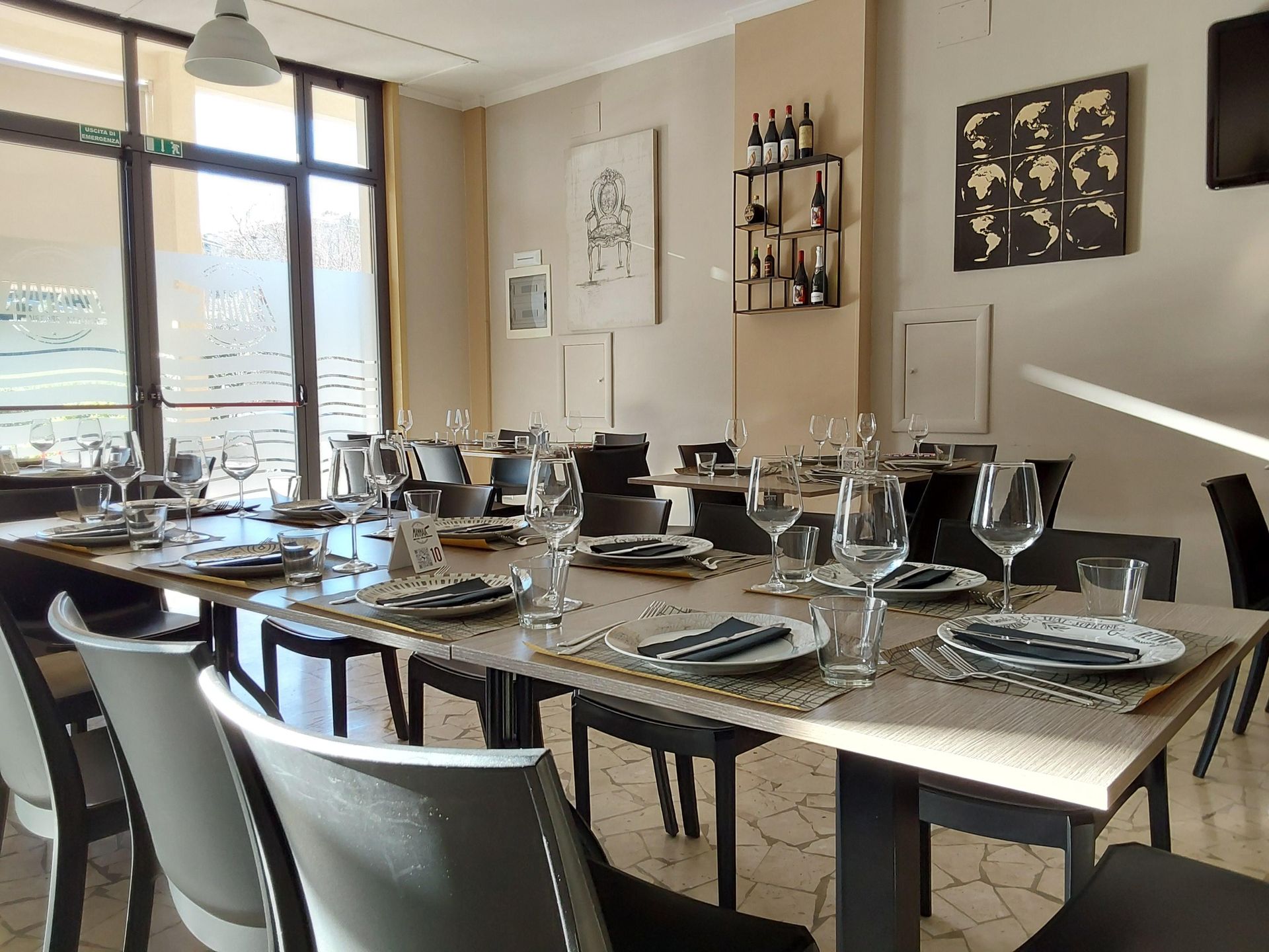 Tavolo da pranzo apparecchiato in una luminosa sala da pranzo moderna con grandi finestre e opere d'arte alle pareti.