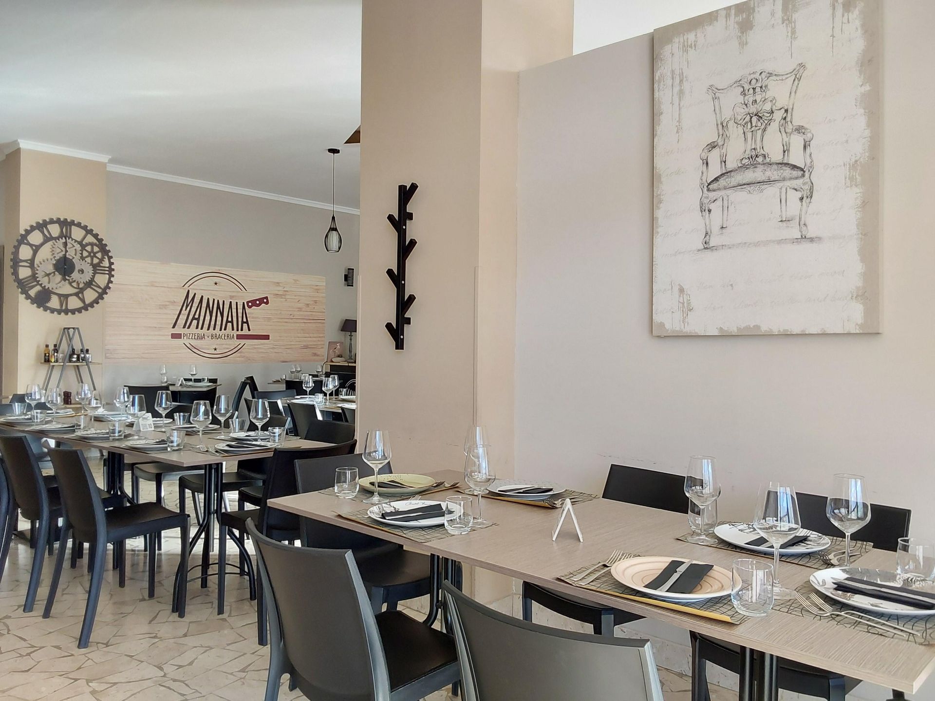 Elegante sala da pranzo di un ristorante con tavoli apparecchiati, sedie nere e opere d'arte alle pareti in delicate tonalità neutre.