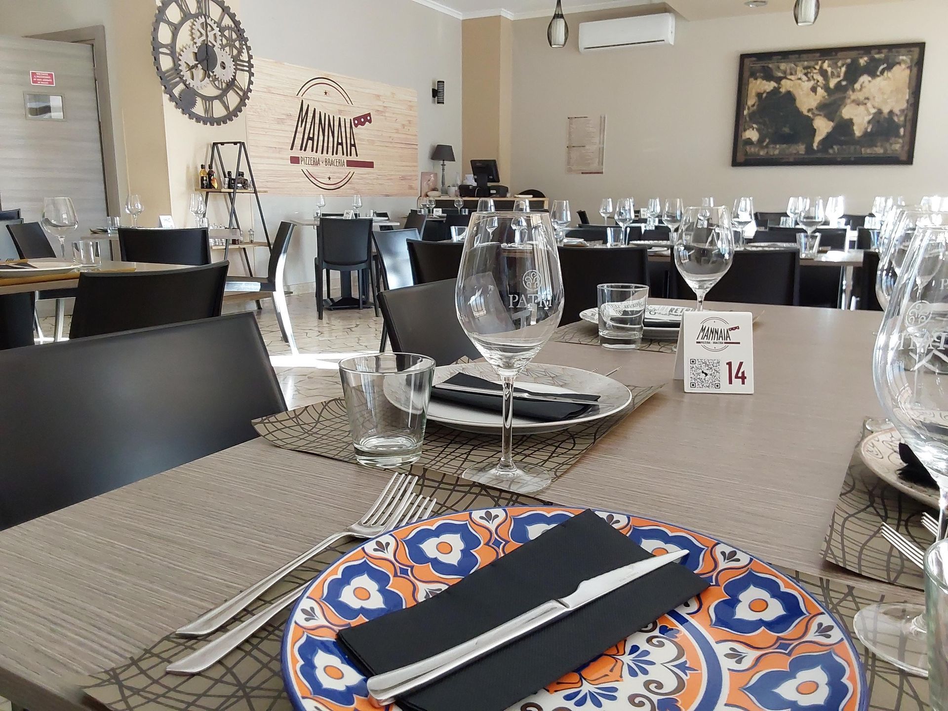 Apparecchiate la tavola in un ristorante luminoso con piatti e bicchieri da vino decorati con motivi blu.