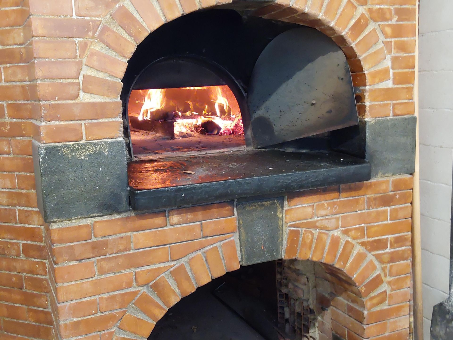 Forno in mattoni con fuoco acceso all'interno dell'arco superiore.