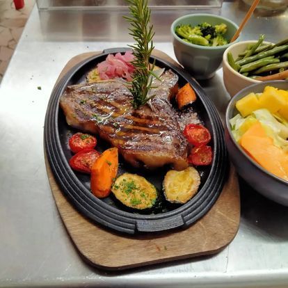 Bistecca alla griglia su un piatto sfrigolante con verdure e contorni su un tavolo di ristorante.