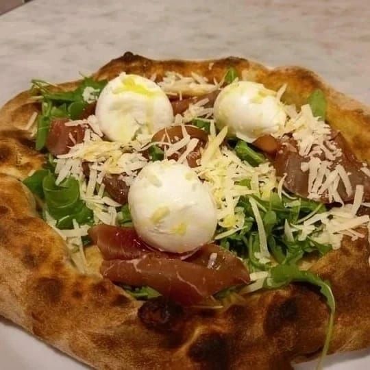 Pizza napoletana condita con rucola, pomodorini, formaggio grattugiato e piccole palline di mozzarella.