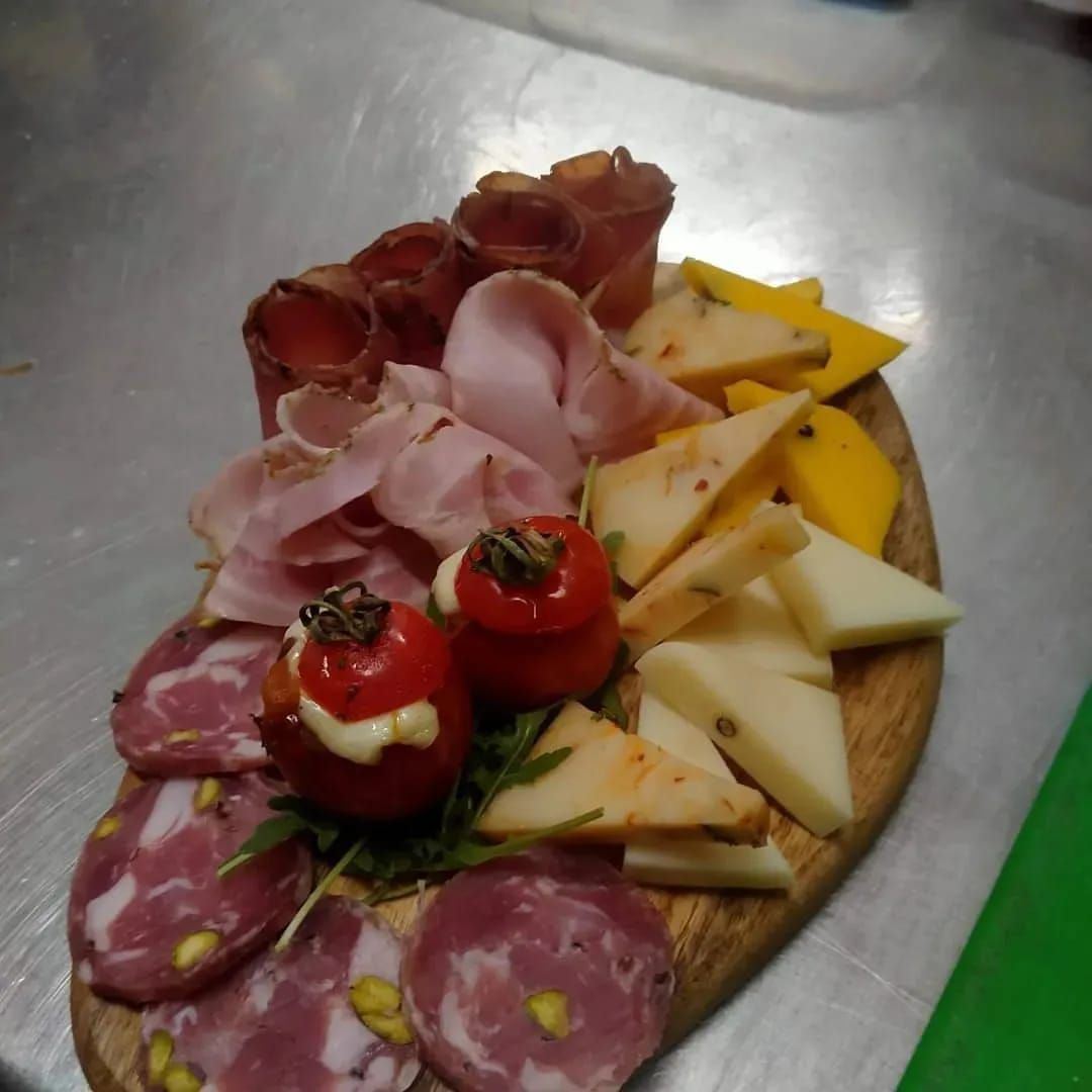 Tagliere di salumi con affettati, formaggi e fragole su un vassoio di legno