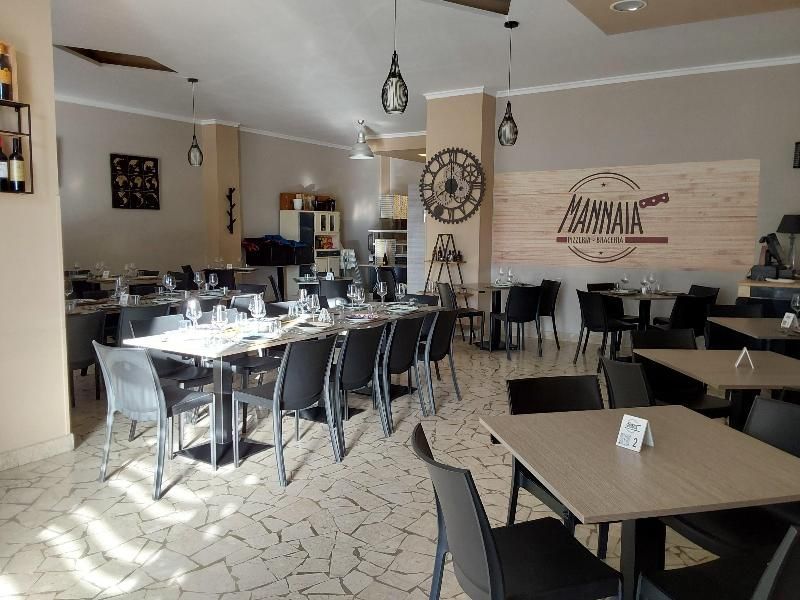Interno luminoso e moderno di una caffetteria con tavoli, sedie e decorazioni murali sotto lampade a sospensione.