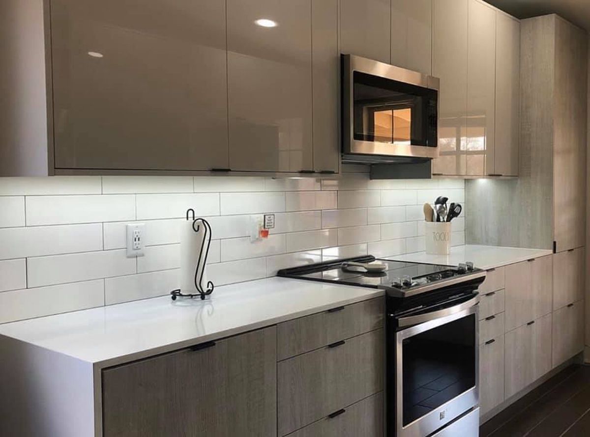 Modern kitchen with gray cabinets, white subway tile backsplash, and stainless steel stove and microwave