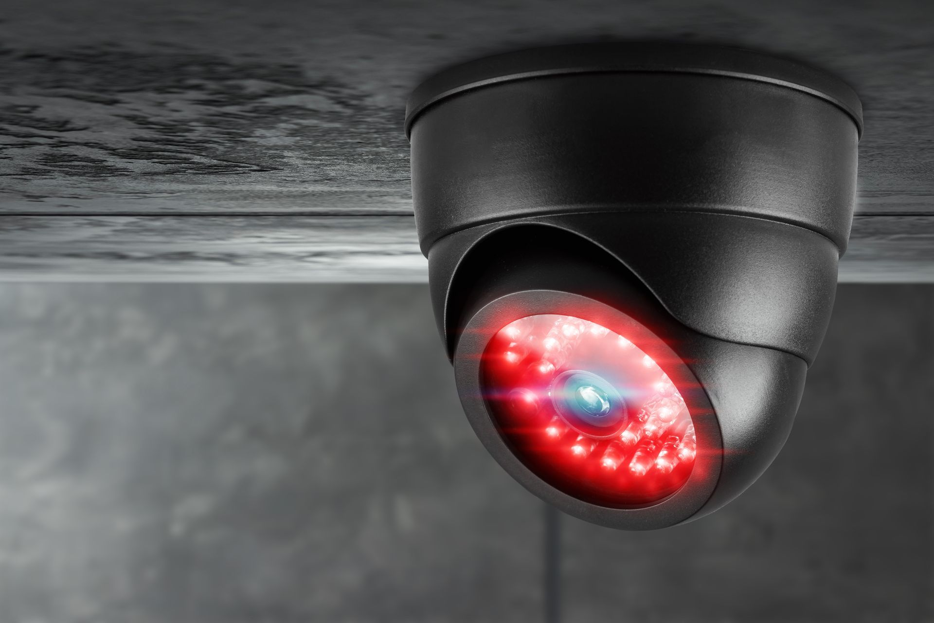 Une caméra de sécurité en forme de dôme noir, fixée au plafond, dont les LED infrarouges de vision nocturne brillent d'un rouge vif.