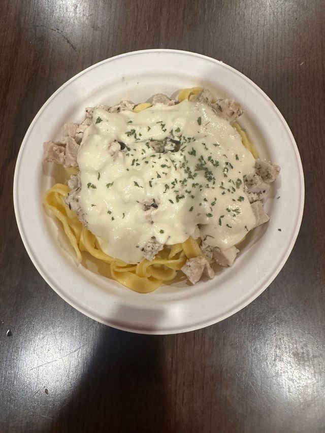Top-down view of a bowl of pasta topped with creamy sauce and herbs on a wooden table