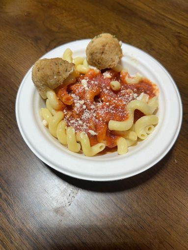 Plate of rotini pasta with red tomato sauce and two meatballs on a wooden table