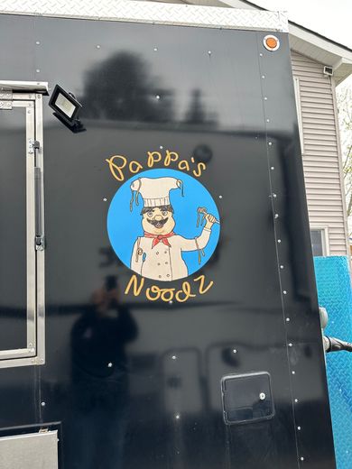 Black trailer door with a blue circular dog logo and yellow text, plus a small mounted light at left